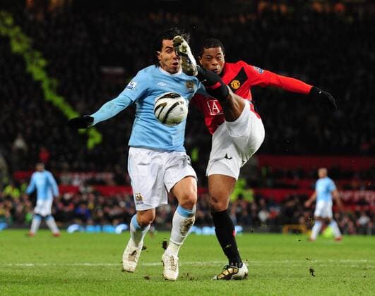 Carlos Tevez (L) of Manchester City challenged by Patrice Evra of Manchester United - Carling Cup, Semi Final 2nd Leg, Manchester United - Manchester City, 27th January, 2010 - EDITORIAL USE ONLY. No use with unauthorised audio, video, data, fixture lists, club league logos or live services. Online in-match use limited to 120 images, no video emulation. No use in betting, games or single club league player publications.