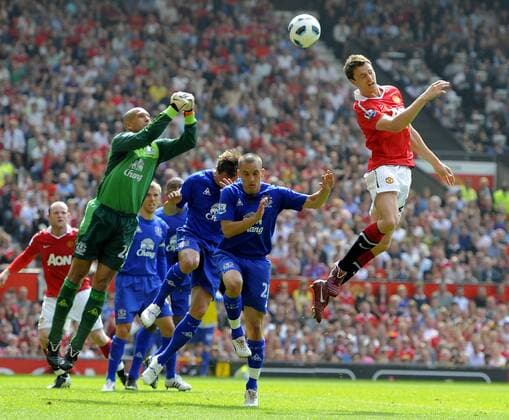 Jonny Evans of Manchester United (R) flicks on a header as Tim Howard of Everton (L) prepares to punch the ball away in the English Premier League football match between Manchester United ManU (red) and Everton FC (blue) at Old Trafford, Manchester, England, on April 23, 2011. EDITORIAL USE ONLY. No use with unauthorised audio, video, data, fixture lists, club league logos or live services. Online in-match use limited to 120 images, no video emulation. No use in betting, games or single club league player publications.