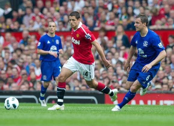 Javier Chicharito Hernandez of Manchester United (C) runs into space past Phil Jagielka of Everton (R) in the English Premier League football match between Manchester United ManU (red) and Everton FC (blue) at Old Trafford, Manchester, England, on April 23, 2011. EDITORIAL USE ONLY. No use with unauthorised audio, video, data, fixture lists, club league logos or live services. Online in-match use limited to 120 images, no video emulation. No use in betting, games or single club league player publications.