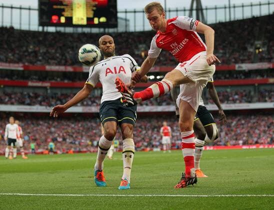 Arsenal s Per Mertesacker tussles with Tottenham s Younes Kaboul - Barclays Premier League - Arsenal vs Tottenham Hotspur - Emirates Stadium - England - 27th September 2014 - EDITORIAL USE ONLY. No use with unauthorised audio, video, data, fixture lists, club league logos or live services. Online in-match use limited to 120 images, no video emulation. No use in betting, games or single club league player publications.