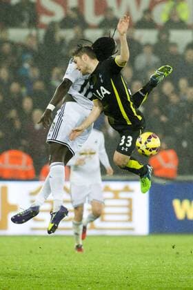 Football - 2014 2015 Premier League - Swansea City vs. Tottenham Hotspur Bafétimbi Gomis of Swansea & Ben Davies Tottenham of Hotspurs collide in the air at The Liberty Stadium. COLORSPORT WINSTON BYNORTH