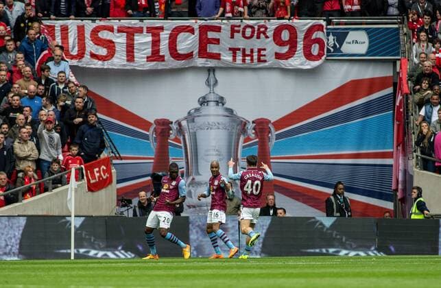 Christian Benteke of Aston Villa celebrates his goal with Fabian Delph and Jack Grealish of Aston Villa in front of the Liverpool fans and the Justice for the 96 banner during the The FA Cup Semi-Final match between Aston Villa and Liverpool at Wembley Stadium, London, England on 19 April 2015. Copyright: xLiamxMcAvoyx 03950093