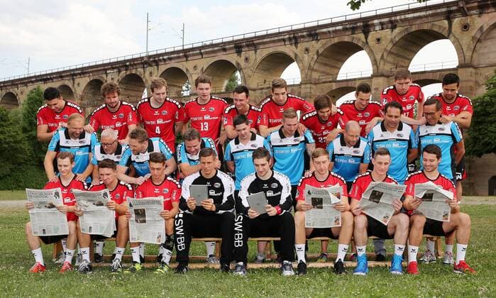 Bietigheim-Bissingen Handball SG BBM Bietigheim Fototermin, Mannschaftsfoto, die Spieler lesen die Ludwigsburger Kreiszeitung Hintere Reihe von Links nach Rechts: Johannes Millenbeck (19), Robin Haller (2), Patrick Rentschler (4), Valentin Schmidt (13), Max Emanuel (68), Nikola Vlahovic (3), Paco Barthe (22), Dominik Claus (7), Gerdas Babarskas (17), Panagiotis Erifopoulos (10). Mittlere Reihe von Links nach Rechts: Hartmut Mayerhoffer (Trainer), Hans-Ulrich Kämpf (TW-Trainer), Nils Heinze (Athletiktrainer), Jens Rith (Teammanager), Lukas Daub (Physio), Max Mauch (Physio), Dr. Christoph Lukas (Mannschaftsarzt), Dr. Aki Karavalakis (Mannschaftsarzt), Dr. Pavel Dolezel (Allg. Medizin). Vordere Reihe von Links nach Rechts: Sören Schmid (5), Jan Asmuth (23), Robin Baumann (18), Jürgen Müller (12), Domenico Ebner (1), Jan Döll (29), Martin Marcec (73), Christian Schäfer (11)