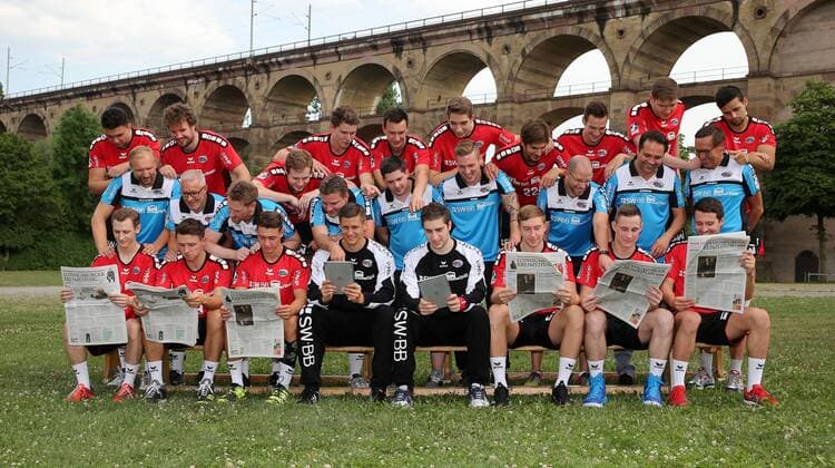 Bietigheim-Bissingen Handball SG BBM Bietigheim Fototermin, Mannschaftsfoto, die Spieler lesen die Ludwigsburger Kreiszeitung Hintere Reihe von Links nach Rechts: Johannes Millenbeck (19), Robin Haller (2), Patrick Rentschler (4), Valentin Schmidt (13), Max Emanuel (68), Nikola Vlahovic (3), Paco Barthe (22), Dominik Claus (7), Gerdas Babarskas (17), Panagiotis Erifopoulos (10). Mittlere Reihe von Links nach Rechts: Hartmut Mayerhoffer (Trainer), Hans-Ulrich Kämpf (TW-Trainer), Nils Heinze (Athletiktrainer), Jens Rith (Teammanager), Lukas Daub (Physio), Max Mauch (Physio), Dr. Christoph Lukas (Mannschaftsarzt), Dr. Aki Karavalakis (Mannschaftsarzt), Dr. Pavel Dolezel (Allg. Medizin). Vordere Reihe von Links nach Rechts: Sören Schmid (5), Jan Asmuth (23), Robin Baumann (18), Jürgen Müller (12), Domenico Ebner (1), Jan Döll (29), Martin Marcec (73), Christian Schäfer (11)