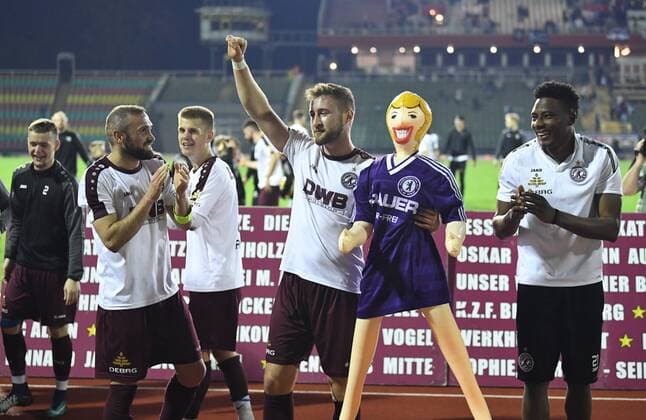 Fussball, Herren, Saison 2017 2018, Halbfinale im Berliner Pilsner-Pokal, BFC Dynamo - Tennis Borussia, Bilal Cubukcu (BFC Dynamo), Vincent Rabiega (BFC Dynamo) mit Gummipuppe aus dem Fanblock im Trikot der Hans-Rosenthal-Elf (war TeBe-Fan), Solomon Okoronkwo (BFC Dynamo), Jubel nach dem Abpfiff, 18.04. 2018, Copyright: xMatthiasxKochx