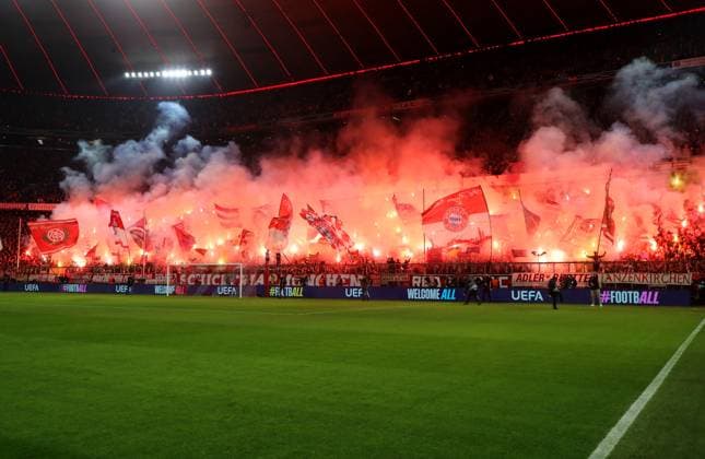 Fussball, Herren, Champions League, Saison 2024 2025, FC Bayern München - Bayer 04 Leverkusen, Achtelfinale Hinspiel,Allianz Arena Pyro, Bengalo, Feuer in der Südkurve zum Spielbeginn, Fans, Fahnen