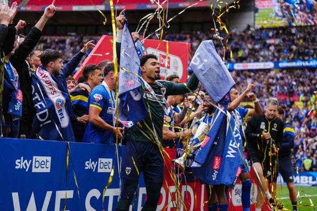 AFC Wimbledon players with the Sky Bet League Two Play-Off Final trophy in front of winners boards AFC Wimbledon v Walsall, EFL Sky Bet League Two, Play-Off Final, Football, Wembley Stadium, London, UK - 26 May 2025 EDITORIAL USE ONLY No use with unauthorised audio, video, data, fixture lists, club league logos or live services. Online in-match use limited to 120 images, no video emulation. No use in betting, games or single club league player publications. Copyright: xJoexToth Shutterstockx 15316459cp