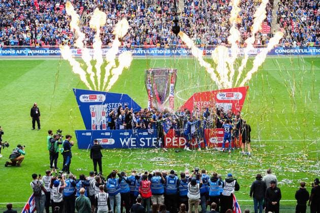 AFC Wimbledon players with the Sky Bet League Two Play-Off Final trophy in front of winners boards We Stepped up Flags AFC Wimbledon v Walsall, EFL Sky Bet League Two, Play-Off Final, Football, Wembley Stadium, London, UK - 26 May 2025 EDITORIAL USE ONLY No use with unauthorised audio, video, data, fixture lists, club league logos or live services. Online in-match use limited to 120 images, no video emulation. No use in betting, games or single club league player publications. Copyright: xAndrewxFosker Shutterstockx 15316458dp