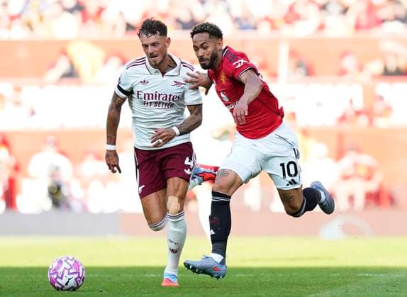 Manchester, England, 17th August 2025. Matheus Cunha of Manchester United, ManU (r) sprints past Ben White of Arsenal (l) during the Manchester United vs Arsenal Premier League match at Old Trafford, Manchester. Picture credit should read: Andrew Yates Sportimage EDITORIAL USE ONLY. No use with unauthorised audio, video, data, fixture lists, club league logos or live services. Online in-match use limited to 120 images, no video emulation. No use in betting, games or single club league player publications. SPI_057_AY_ManUtd_Arsenalx SPI-4072-0076