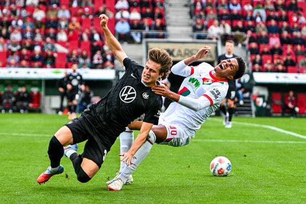GER, 1. FBL, FC Augsburg vs VfL Wolfsburg 04.10.2025, WWK-Arena, Augsburg, GER, 1. FBL, FC Augsburg vs VfL Wolfsburg, im Bild Mattias Svanberg (VfL Wolfsburg, 32) trifft Noahkai Banks (FC Augsburg, 40) mit der Schulter im Gesicht, Foul