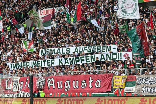 GER, 1. FBL, FC Augsburg vs VfL Wolfsburg 04.10.2025, WWK-Arena, Augsburg, GER, 1. FBL, FC Augsburg vs VfL Wolfsburg, im Bild Banner der Augsburger Fans fuer den schwer verletzten Fan aus Heidenheim, niemals aufgeben, immer weiter kaempfen Andi