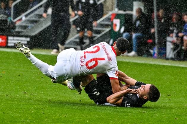 GER, 1. FBL, FC Augsburg vs VfL Wolfsburg 04.10.2025, WWK-Arena, Augsburg, GER, 1. FBL, FC Augsburg vs VfL Wolfsburg, im Bild Elias Saad (FC Augsburg, 26) stuerzt auf Kilian Fischer (VfL Wolfsburg, 2)