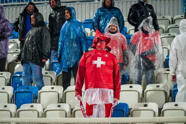 Fussball WM-Qualifikation 2025 26, 10. Spieltag Kosovo vs Schweiz Fadil-Vokrri-Stadion (Pristina): Pristina, Kosovo, Europa: Schweizer Fans im Starkregen, rot gekleidet, Supporter mit bemaltem Gesicht, Schals Schweiz Suisse SvizzerA Svizra, Ponchos, Fanblock, Emotionen, Auswärtssupport, Stimmung, Nässe, Wetterlage, Qualifikation, Fußballkultur, Medienrelevanz: Fanverhalten, Wetter, Sicherheit, Matchday. Pristina Kosovo Copyright: xJOERANxSTEINSIEKx