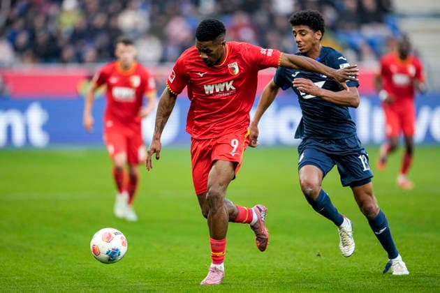 v.li.: Samuel Essende (FCA, 9), Bernardo Fernandes da Silva Junior (Hoffenheim, 13), Zweikampf, Spielszene, Duell, duel, tackle, tackling, Dynamik, Action, Aktion, 29.11.2025, Sinsheim (Deutschland), Fussball, Bundesliga, TSG 1899 Hoffenheim - FC Augsburg, DFB DFL REGULATIONS PROHIBIT ANY USE OF PHOTOGRAPHS AS IMAGE SEQUENCES AND OR QUASI-VIDEO.