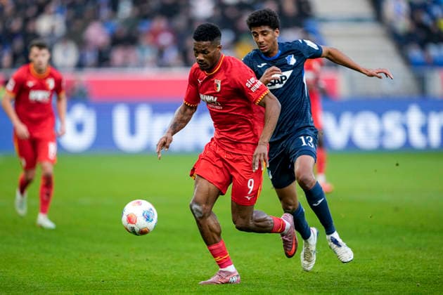 v.li.: Samuel Essende (FCA, 9), Bernardo Fernandes da Silva Junior (Hoffenheim, 13), Zweikampf, Spielszene, Duell, duel, tackle, tackling, Dynamik, Action, Aktion, 29.11.2025, Sinsheim (Deutschland), Fussball, Bundesliga, TSG 1899 Hoffenheim - FC Augsburg, DFB DFL REGULATIONS PROHIBIT ANY USE OF PHOTOGRAPHS AS IMAGE SEQUENCES AND OR QUASI-VIDEO.