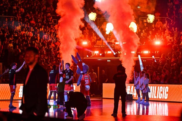 GER, BBL, ratiopharm Ulm vs Rasta Vechta 13.12.2025, ratiopharm arena, Neu-Ulm, GER, BBL, ratiopharm Ulm vs Rasta Vechta, im Bild Ulmer Spieler werden mit Lichteffekten und Nebel in der Halle begruesst, Teo Milicic (Ulm, 44), das Ulmer Maskottchen Spass hat passend zum Weihnachtspiel eine Weihnachtsmuetze