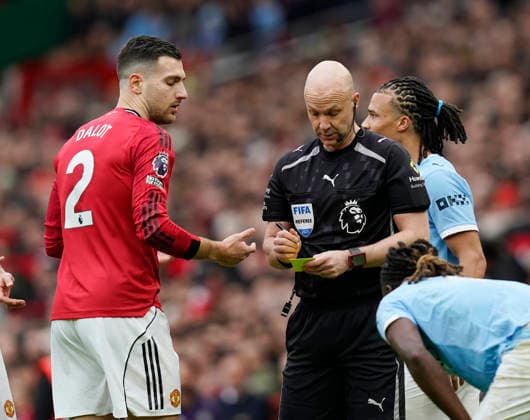 Manchester, England, 17th January 2026. Diogo Dalot of Manchester United, ManU receives a yellow card from referee Anthony Taylor during the Manchester United vs Manchester City Premier League match at Old Trafford, Manchester. Picture credit should read: Andrew Yates Sportimage EDITORIAL USE ONLY. No use with unauthorised audio, video, data, fixture lists, club league logos or live services. Online in-match use limited to 120 images, no video emulation. No use in betting, games or single club league player publications. SPI_048_AY_ManUtd_ManCity SPI-4456-0048