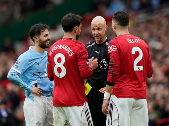 Manchester, England, 17th January 2026. Referee Anthony Taylor talks to captain Bruno Fernandes of Manchester United, ManU before issuing a yellow card to Diogo Dalot of Manchester United (r) as Bernardo Silva of Manchester City looks on (l) during the Manchester United vs Manchester City Premier League match at Old Trafford, Manchester. Picture credit should read: Andrew Yates Sportimage EDITORIAL USE ONLY. No use with unauthorised audio, video, data, fixture lists, club league logos or live services. Online in-match use limited to 120 images, no video emulation. No use in betting, games or single club league player publications. SPI_050_AY_ManUtd_ManCity SPI-4456-0050