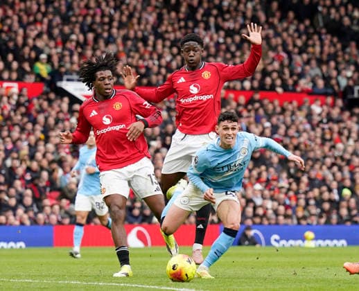 Manchester, England, 17th January 2026. Patrick Dorgu of Manchester United, ManU (l) and Kobbie Mainoo of Manchester United fail to stop Phil Foden of Manchester City during the Manchester United vs Manchester City Premier League match at Old Trafford, Manchester. Picture credit should read: Andrew Yates Sportimage EDITORIAL USE ONLY. No use with unauthorised audio, video, data, fixture lists, club league logos or live services. Online in-match use limited to 120 images, no video emulation. No use in betting, games or single club league player publications. SPI_065_AY_ManUtd_ManCity SPI-4456-0063