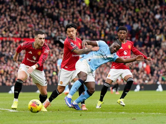 Manchester, England, 17th January 2026. Diogo Dalot, Lisandro Martinez and Kobbie Mainoo of Manchester United, ManU combine to stop Jeremy Doku of Manchester City during the Manchester United vs Manchester City Premier League match at Old Trafford, Manchester. Picture credit should read: Andrew Yates Sportimage EDITORIAL USE ONLY. No use with unauthorised audio, video, data, fixture lists, club league logos or live services. Online in-match use limited to 120 images, no video emulation. No use in betting, games or single club league player publications. SPI_063_AY_ManUtd_ManCity SPI-4456-0064