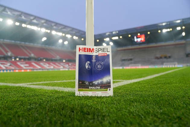 Fussball: UEFA Europa League 2025 26, 7. Spieltag SC Freiburg vs Maccabi Tel Aviv Europa-Park-Stadion (Freiburg): Das Stadionmagazin Heimspiel mit Vereinslogos und UEFA-Europa-League-Branding steht am Spielfeldrand auf dem Rasen. Abendspiel, Flutlicht, leeres Stadion vor Anpfiff, internationale Begegnung, Sicherheit, Organisation, Spielvorbereitung, Fußball, UEFA, Europa League, SC Freiburg, Maccabi Tel Aviv, Freiburg. Copyright: xJOERANxSTEINSIEKx