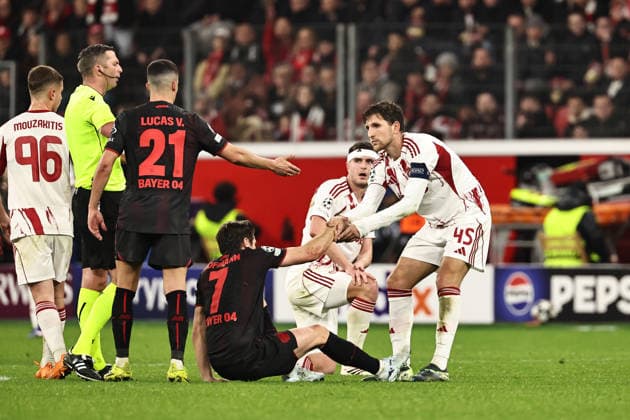 GER, Champions League, Bayer Leverkusen vs Olympiakos Piräus 24.02.2026, BayArena, Leverkusen, GER, Champions League, Bayer Leverkusen vs Olympiakos Piräus im Bild Kapitän Panagiotis Retsos (Olympiakos Piräus, 45, weiß) hilft Jonas Hofmann (Bayer 04 Leverkusen, 07, schwarz) unter den Augen von Schiedsrichter Michael Oliver (England) wieder auf die Beine