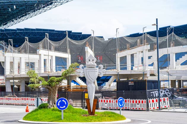 Spanien: Fussball UEFA Europa-League 2025 - 2026, Viertelfinale (Rückspiel) - Celta Vigo vs SC Freiburg - Balaidos (Vigo): Stadionumfeld, Estadio Balaidos, Stadion, Sportstätte, Außenansicht, Detailansicht, Baustelle, Umbau, Bauarbeiten, Infrastruktur, Rohbau, Tribünenbereich, Sitzreihen, Fangnetze, Sicherheitsnetze, Absperrung, Baustellenabsicherung, Sicherheitszaun, Container, Graffiti, Schriftzug COPASA, Kreisverkehr, Verkehrsschild, Rundverkehr, Straßenverkehr, Mobilität, Stadtbild, urbanes Umfeld, Kunstobjekt, Wappen Celta Vigo im Vordergrund, Begrünung, Baum, Tageslicht Copyright: xJOERANxSTEINSIEKx