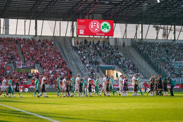 Deutschland: Fussball 2. Bundesliga Relegation 2025 - 2026 - Rot Weiss Essen vs SpVgg Greuther-Fürth - Stadion an der Hafenstraße (Essen): Mannschaften von Rot Weiss Essen und SpVgg Greuther-Fürth betreten gemeinsam mit Einlaufkindern das Spielfeld vor ausverkauftem Stadion. Blick auf Heim- und Gästefans sowie Videowürfel mit Relegation-Branding. Fußballfans, Choreografie, Traditionsvereine, Aufstiegskampf, 2. Bundesliga, Matchday, Stadionatmosphäre, Heimblock, Gästeblock, Fußballkultur, Ruhrgebiet, Nordrhein-Westfalen, Sportevent, Deutsche Fussball Liga, Stadionarchitektur, Abendsonne, STEINSIEK.CH Copyright: xJOERANxSTEINSIEKx