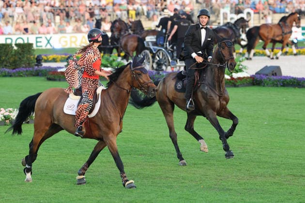 Richard Vogel und Luciana Diniz im Tempo gemeinsam in Bond-Stunt-Feeling über die Hindernisse, Konzert Pferd & Sinfonie, Rahmenprogramm, Motto des Abends: James Bond, Weltfest des Pferdesports, World Equestrian Festival, TSCHIO Aachen 2026, TSCHIO statt CHIO 2026, Aachener Soers, 22. bis 24. Mai 2026, Reitsport, 23.05.2026, Aachen Aachener Soers Deutschland