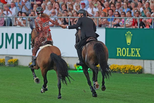 Richard Vogel und Luciana Diniz im Tempo gemeinsam in Bond-Stunt-Feeling über die Hindernisse, Konzert Pferd & Sinfonie, Rahmenprogramm, Motto des Abends: James Bond, Weltfest des Pferdesports, World Equestrian Festival, TSCHIO Aachen 2026, TSCHIO statt CHIO 2026, Aachener Soers, 22. bis 24. Mai 2026, Reitsport, 23.05.2026, Aachen Aachener Soers Deutschland
