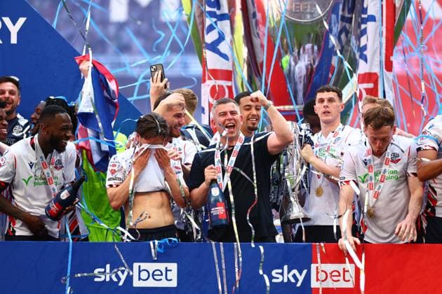 Bolton Wanderers manager Steven Schumacher of Bolton Wanderers with Eoin Toal , Josh Sheehan and the rest of the team celebrate with the League One Play off final trophy Bolton Wanderers v Stockport County, EFL Sky Bet League One, Play-Off Final, Football, Wembley Stadium, London, UK - 24 May 2026London Wembley Stadium United Kingdom EDITORIAL USE ONLY No use with unauthorised audio, video, data, fixture lists, club league logos or live services. Online in-match use limited to 120 images, no video emulation. No use in betting, games or single club league player publications. Copyright: xJamesxMarsh Shutterstockx 16889809db