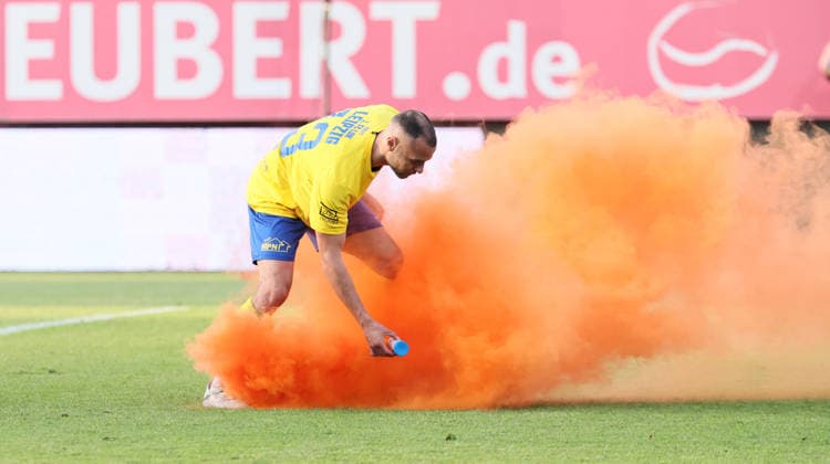 Würzburg, 01.06.2026, Stadion am Dallenberg, Fußball, Aufstiegspiele zur 3.Liga, Rückspiel , FWK Würzburger Kickers vs. 1.FC Lok Leipzig , Im Bild: Djamal Ziane (13, Lok) entfernt einen auf das Feld geworfenen Rauchtopf. , Nur zur redaktionellen Nutzung. Only editorial use. NOFV DFB regulations prohibit any use of photographs as image sequences and or quasi-video. ,
