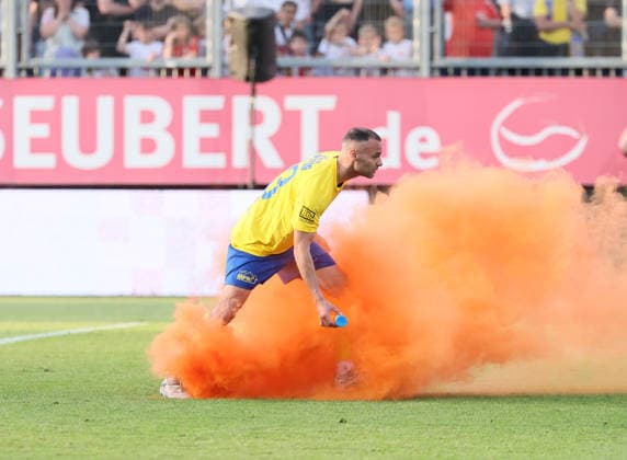 Würzburg, 01.06.2026, Stadion am Dallenberg, Fußball, Aufstiegspiele zur 3.Liga, Rückspiel , FWK Würzburger Kickers vs. 1.FC Lok Leipzig , Im Bild: Djamal Ziane (13, Lok) entfernt einen auf das Feld geworfenen Rauchtopf. , Nur zur redaktionellen Nutzung. Only editorial use. NOFV DFB regulations prohibit any use of photographs as image sequences and or quasi-video. ,
