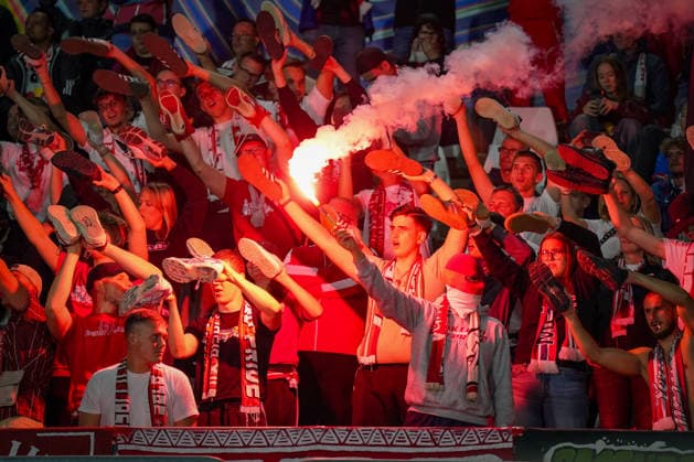 Italien: Fussball UEFA Champions League 2026 - 2027, 1. Spieltag - Como 1907 vs RB Leipzig - Giuseppe Sinigaglia (Como): Fans von RB Leipzig im Gästeblock halten bei einer Choreographie ihre Schuhe in die Höhe, während ein Fan Pyrotechnik Bengalo zündet. Fußball, Champions League, RB Leipzig, Auswärtsfans, Zuschauer, Fans, Ultras, Fankultur, Fanchoreo, Choreographie, Pyrotechnik, Bengalo, Rauch, Gästetribüne, Fanblock, Stimmung, Emotionen. Copyright: xJOERANxSTEINSIEKx
