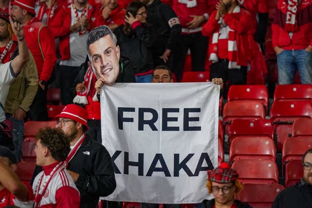 Fussball UEFA Nations League 2026 - 2027, 2. Spieltag - Schottland vs Schweiz - Hampden Park (Glasgow): Schweizer Fans im Hampden Park beim Spiel Schottland gegen Schweiz. Ein Fan hält ein Transparent mit der Aufschrift FREE XHAKA sowie eine Maske mit dem Gesicht von Granit Xhaka hoch. Fussball, UEFA Nations League, Schweiz, Granit Xhaka, Fans, Zuschauer, Tribüne, Transparent, Spruchband, Protest, Solidarität, Fankultur, Schweizer Nationalmannschaft, SFV, Hampden Park, Glasgow. Copyright: xJOERANxSTEINSIEKx