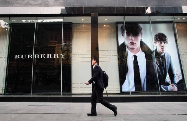 --File--A pedestrian walks past a Burberry boutique in Shanghai, China, 6 April 2012. Burberry has been awarded ¡ê63 million ($100 million) in damages after taking a network of Chinese counterfeiters to court. WWD report that the defendants, who ran websites such as yesburberryvision.com and buyburberry.com, were known to have sold at least 22 different product types all bearing imitations of the British heritage brands various trademarks, such as its iconic plaid check and equestrian knight logo. The resolution of the case, which was originally filed in January at Manhattan Federal Court, comes after months of waiting for the defendants to reply to the accusations and appear in court - neither of which was ever done. The domain names for all the infringing sites will now be transferred to Burberry, allowing the brand to cut off any associated internet providers, web designers, sponso 20120406_27120