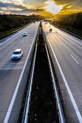 Autos und Lkw fahren auf der A2 bei Helmstedt (Niedersachsen) im Sonnenuntergang.