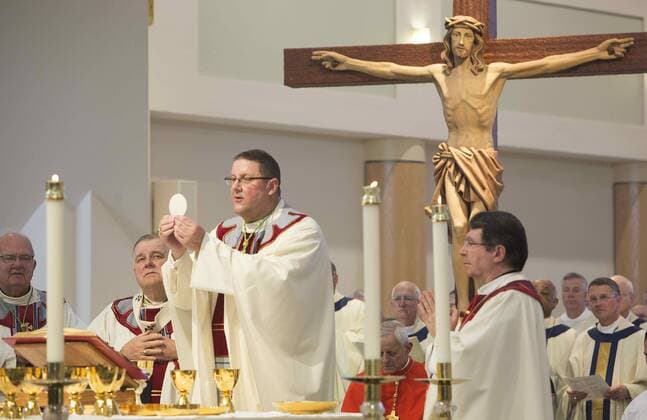 January 4, 2017 - St. Petersburg, Florida, U.S. - SCOTT KEELER Times. New Bishop Gregory L. Parkes, center, Diocese of St. Petersburg, offers the communion wafter in front of parishioners, 1 4 16 at the Cathedral of St. Jude the Apostle during his installment. Parkes is the fifth Bishop in the Diocese. on the far left is retiring Bishop Robert N. Lynch, and left, The Most Reverend Thomas G. Wenski, Archbishop of Miami. Right is The Most Reverend Christophe Pierre, Apostolic Nuncio tot the United States. St. Petersburg U.S. - ZUMAs70_ 20170104_zan_s70_040