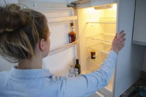 Gestellte Aufnahme: Eine Frau schaut in einen leeren Kuehlschrank. Berlin, 13.02.2018. Berlin Deutschland