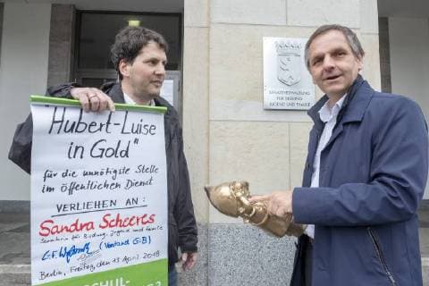 Negativ Zwerg Deutschland, Berlin, 13.04.2018, Negativpreis für Ausschreibung Oberregierungsrat Öffentlichkeitsarbeit Taskforce Schulbau verliehen, Verleihung Negativpreis Hubert-Luise in Gold (Zwerg) für die unnötigste Stelle im öffentlichen Dienst, durch Aktive von GiB (Gemeingut in BürgerInnenhand) der Bildungssenatorin Sandra Scheeres, Thorsten Metter, Leiter der Pressestelle der Senatsverwaltung für Bildung (rechts) nahm den Preis stellvertretend entgegen, die Laudatio hielt Carl Waßmuth (links) , Sprecher von Gemeingut in BürgerInnenhand (GiB), vor der Senatsverwaltung für Bildung, Jugend und Familie, Â