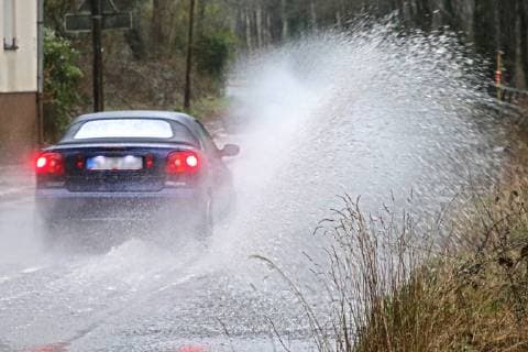 Gefährliche Straßenverhältnisse bei Starkregen. Das Wasser von einer nach Starkregen überfluteten Straße wird von den Autos in die Luft gerissen und sorgt bei vielen Fahrern für Schrecksekunden. Essen Nordrhein-Westfalen Germany - Deutschland Überruhr