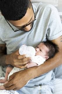 Father bottle-feeding his newborn baby in bed model released Symbolfoto property released ERRF01312