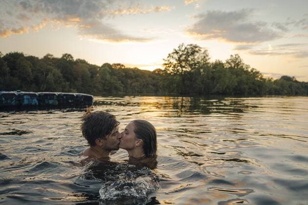 Young couple swimming in lake, kissing at sunset model released Symbolfoto GUSF02323