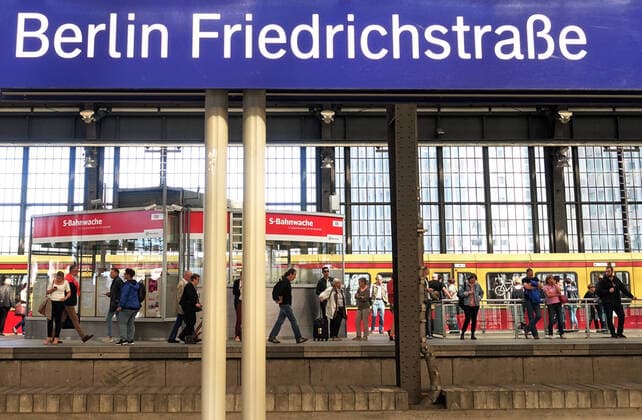 06.09.2019, Berlin, GER - Reisende auf einem Bahnsteig im Bahnhof Friedrichstrasse. (Alltag, Bahn, Bahnhof, Bahnstation, Bahnsteig, Bahnverkehr, befoerdern, Befoerderung, Berlin, deutsch, Deutschland, Europa, europaeisch, Friedrichstrasse, Gesellschaft, innen, Innenaufnahme, Jahreszeit, Menschen, Nahverkehr, oeffentlicher Nahverkehr, oeffentlicher Personennahverkehr, oeffentlicher Personennahverker, OEPNV, Personen, Personenbefoerderung, Personentransport, QF, Querformat, S Bahn, S-Bahn, S-Bahn Berlin GmbH, S-Bahnhof, Schiene, Schild, Sommer, Stadt, Stadtbahn, Stadtverkehr, Station, Stationsschild, Transport, transportieren, Transportmittel, Verkehr, Verkehrsmittel, Westeuropa, Wirtschaft, Zug) 190906D807BERLIN.JPG
