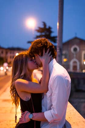 Affectionate young couple kissing inon a bridge at night, Verona, Italy model released Symbolfoto GIOF07025
