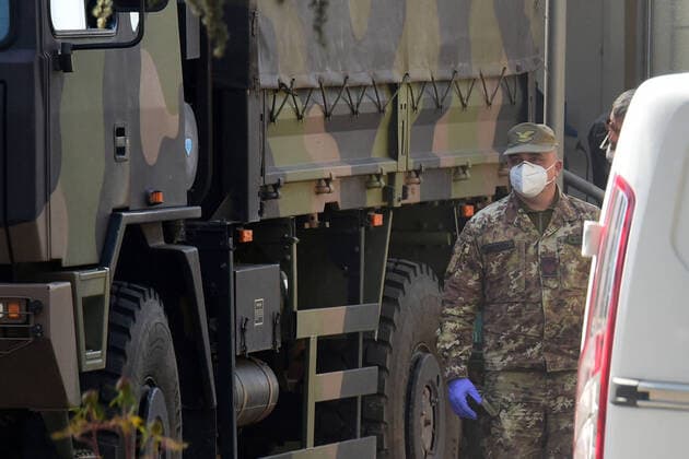 (200331) -- BOLOGNA (ITALY), March 31, 2020 (Xinhua) -- A soldier is seen near a military truck carrying bodies of patients who died from COVID-19 infections from Lombardy, in Bologna, Italy, on March 31, 2020. The COVID-19 pandemic continued to advance in locked down Italy on Tuesday, bringing the total number of infections, fatalities and recoveries to 105,792, according to the latest data released by the country s Civil Protection Department. (Photo by Gianni Schicchi Xinhua) ITALY-BOLOGNA-COVID-19-CASES