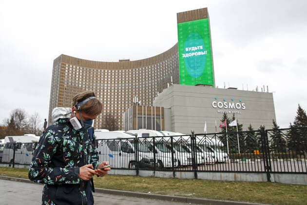 MOSCOW, RUSSIA - APRIL 2, 2020: A man walking by the building of the Cosmos Hotel with a screen displaying a sign Be healthy . The Moscow authorities imposed home isolation for all Moscow residents, regardless of their age, and restrictions on movement within the city, effective since March 30, 2020, as a measure to contain the spread of the COVID-19 coronavirus infection. Violations of the stay-at-home order carry fines ranging from 1,000 to 40,000 rubles for non-infected people, and up to 1m rubles or imprisonment for up to 3 years for infected people, depending on the severity of consequences. Artyom Geodakyan TASS TS0D43A2