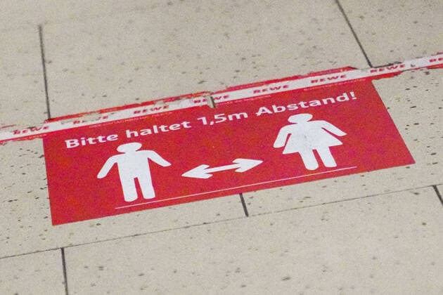 Eindrücke aus Sandhausen in Baden-Württemberg in den Tagen der Corona Kontaktsperre, Coronakrise, das Bild zeigt eine Bodenmarkierung in einem REWE Supermarkt, der die Kunden auffordert, Abstand zu halten, Aufschrift: Bitte haltet 1,5 Meter Abstand, Hinweis, Hinweistafel, Hinweisschild, Aufforderung, Kontaktverbot, Symbolfoto, Symbolbild, Symbol, Einkaufen, 04.04.2020, Sandhausen (Deutschland), News, Feature, Impressionen aus Sandhausen