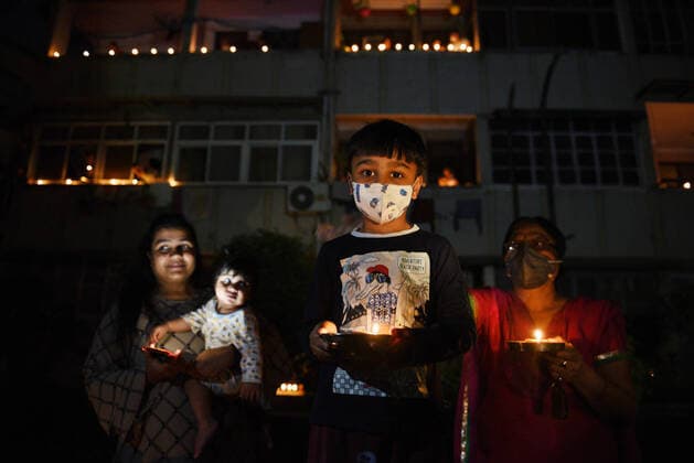 NEW DELHI, INDIA APRIL 5: People with phone lights and earthen lamps (diyas) in a show of solidarity and support for frontline workers, on day twelve of the nationwide lockdown to combat coronavirus, at Meena Appartments, Patparganj, on April 5, 2020 in New Delhi, India. Millions of Indians across the country switched off lights at their homes and lit candles and diyas or turned on mobile phone torches on Sunday night, responding to Prime Minister Narendra Modi s appeal to show the nation s collective resolve and solidarity in its fight against coronavirus with this symbolic gesture. (Photo by Ajay Aggarwal Hindustan Times ) Millions Of Indians Light Candles, Diyas, Turn On Mobile Phone Torches After Prime Minister Modi?s Appeal