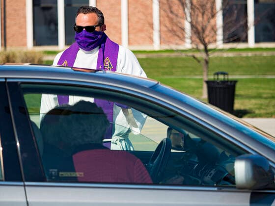 Coronavirus in den USA, Drive-Through Gottesdienst zum Auftakt der Karwoche in Des Moines, Iowa April 5, 2020, Des Moines, Iowa, U.S: Rev. RUSSELL LACKEY follows Social Distancing guidelines while he talks to parishioners during a drive through Palm Sunday service sponsored by Luther Memorial Church on the campus of Grand View University in Des Moines. About 150 people attended the service. They remained in their cars while the ministers read a short passage from the Bible, handed out palms and blessed them. On Sunday, 05 April, Iowa reported 868 confirmed cases of the Novel Coronavirus (SARS-CoV-2) and COVID-19. There have been 22 deaths attributed to COVID-19 in Iowa. Restaurants, bars, movie theaters, places that draw crowds are closed until 30 April. The Governor has not ordered shelter in place but several Mayors, including the Mayor of Des Moines, have asked residents to stay in their homes for all but essential needs. - ZUMAk94_ 20200405_zaf_k94_003 Copyright: xJackxKurtzx
